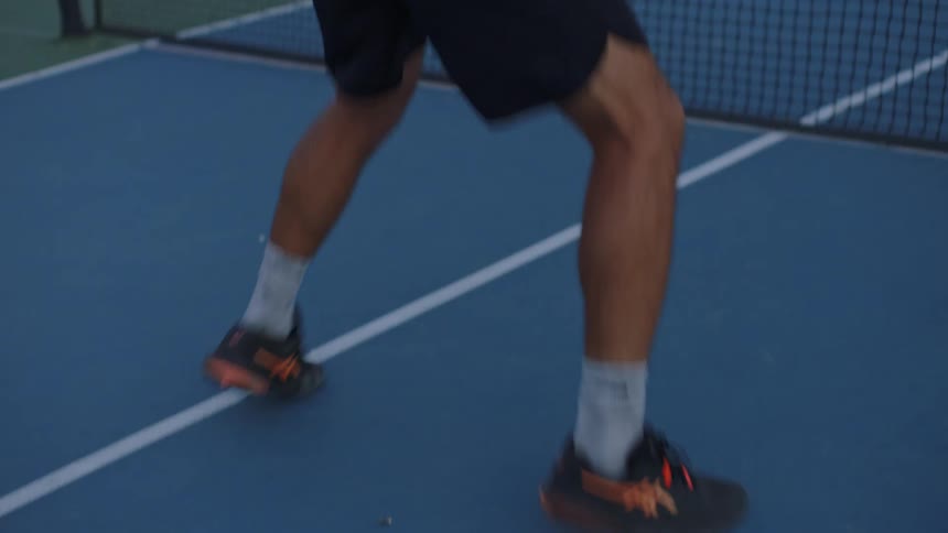 A tennis player swings their racket to hit the ball then follows through with a powerful dynamic motion on the court