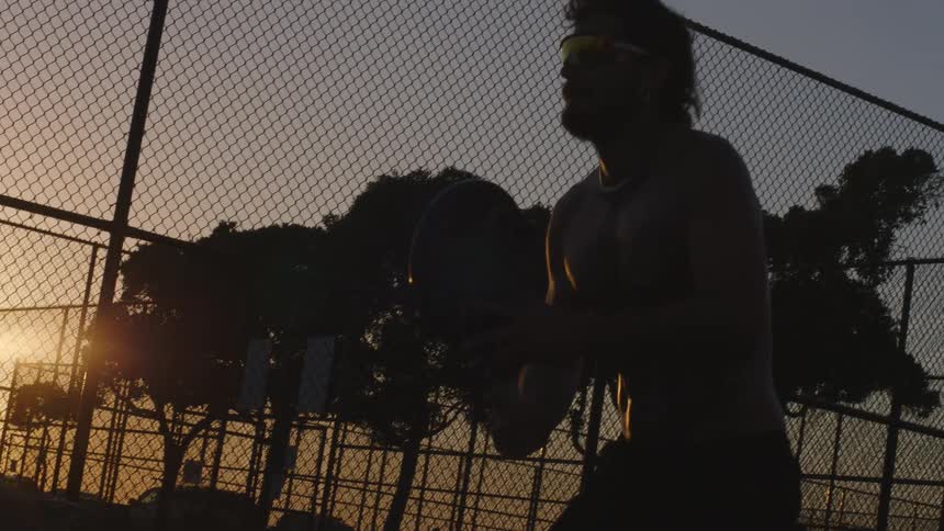 Player holds the racket near the net on a fenced outdoor sports court at dusk
