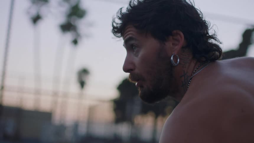 Man in an outdoor setting at dusk with a focused expression