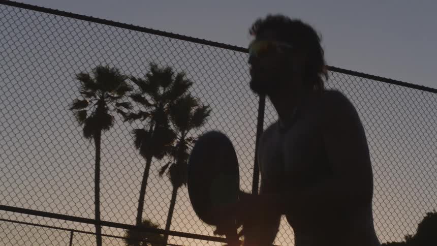 Man in silhouette with a racket practicing sports outdoors