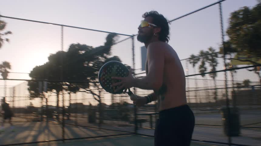 Man with a racket judging on a sports court at dusk