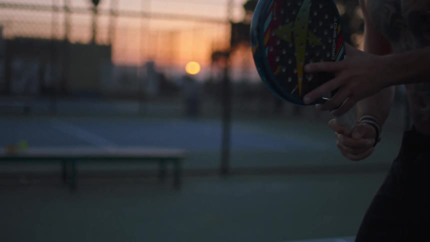 Shirtless man holding a racket and playing on an outdoor court