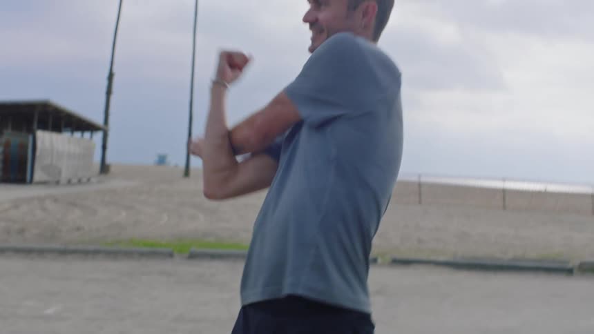 Man outdoors stretching his leg and arm