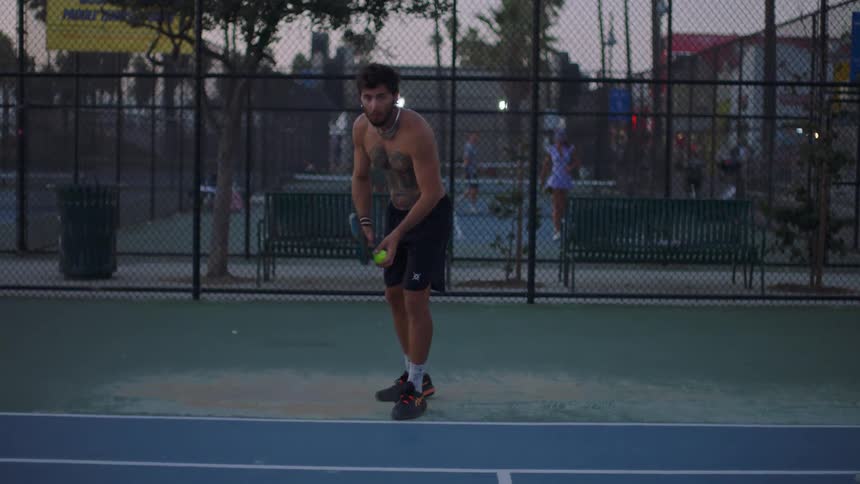 Man throwing a tennis ball on an outdoor court