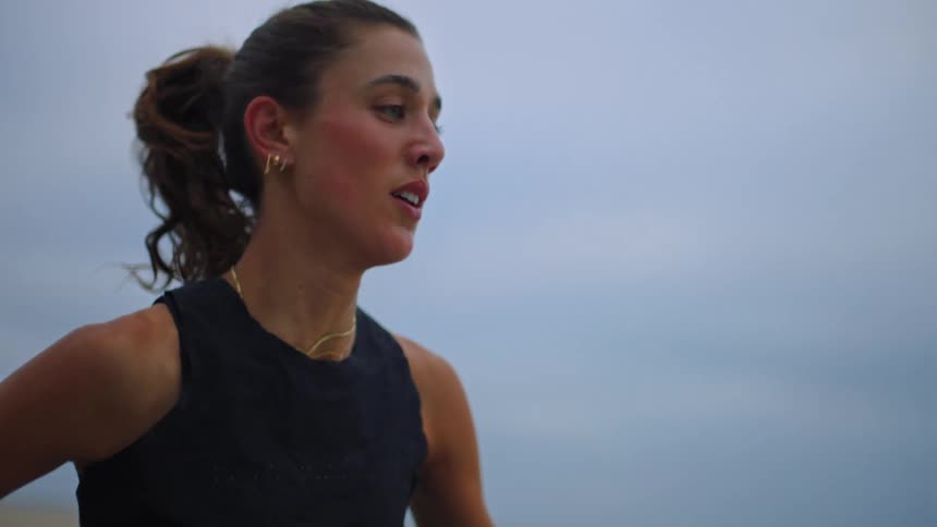 Close up portrait of a young woman jogging outdoors during a fitness session