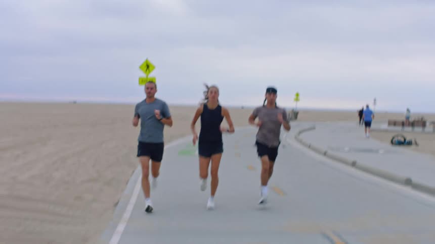 Two men and a woman running on a cloudy day