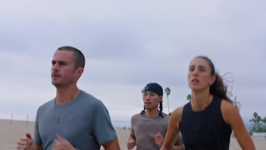 Group of three people running along the beach