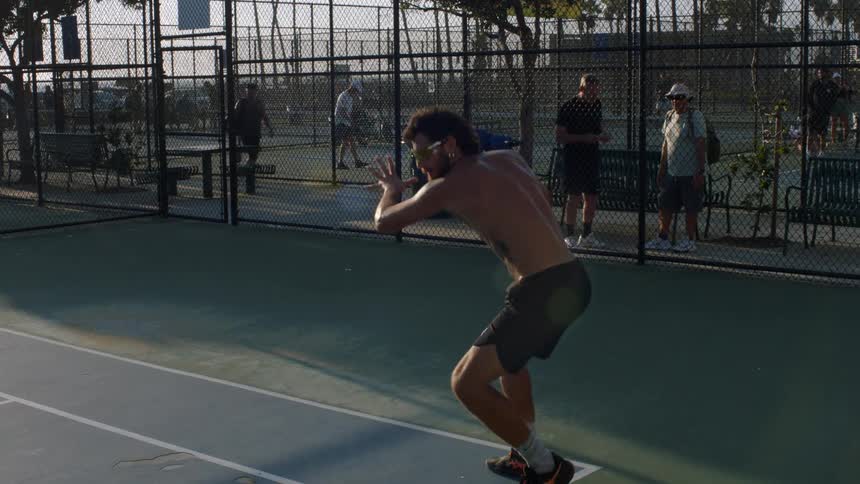 A man swinging a racket while playing racquetball on an indoor court