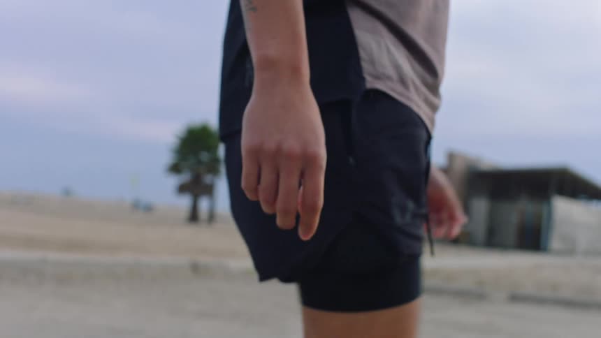 A man in black shorts is stretching his legs