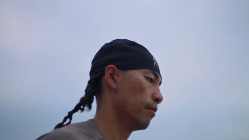 Man with a bandana on his head running outdoors on a cloudy day