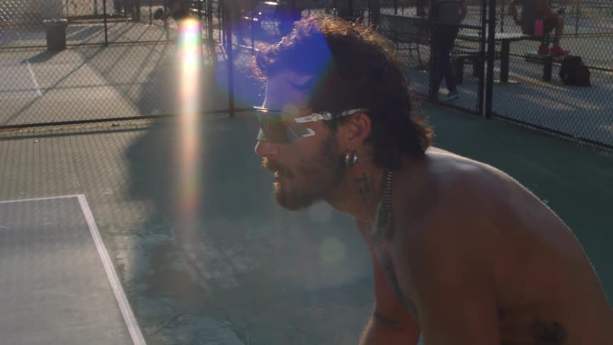 Close up of a young man playing tennis at an outdoor court during daytime