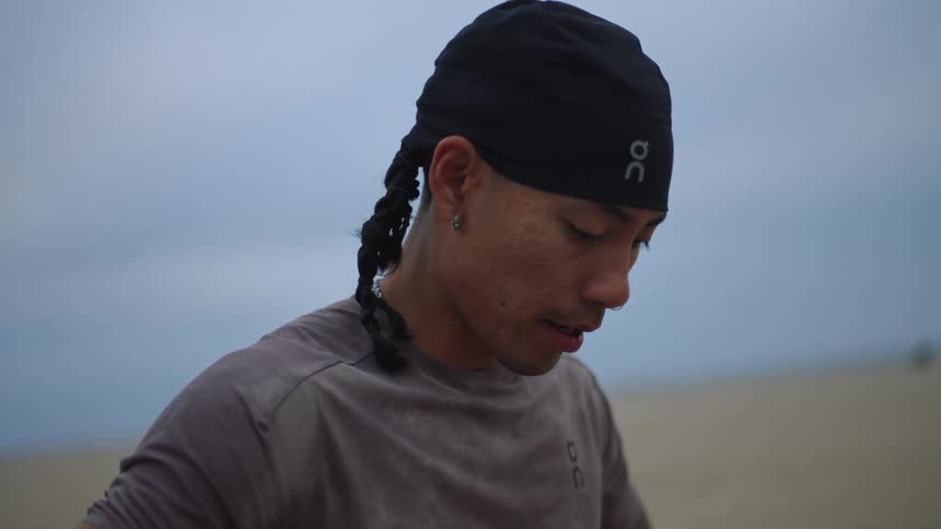 Young man breathes deeply while standing on the beach during the daytime