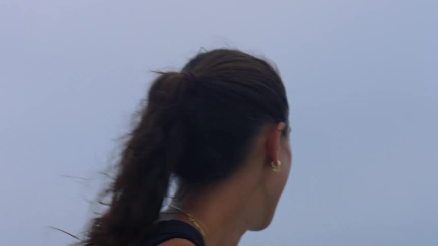 Woman with her hair tied back smiling outdoors