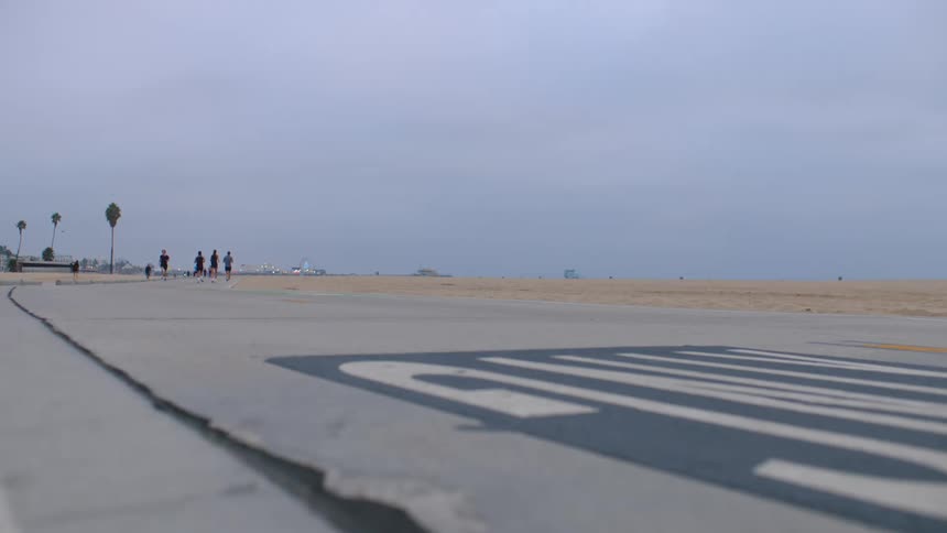 A group of people jogging toward the beach at midday
