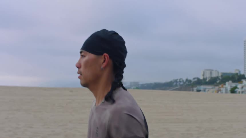 Man and a woman running along the beach on a cloudy day