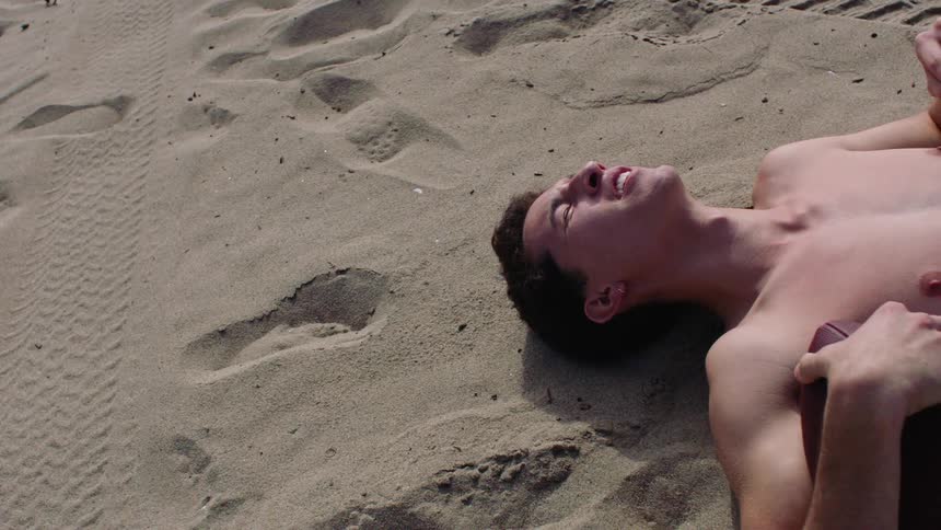 Man lying on the sand holding a sports ball
