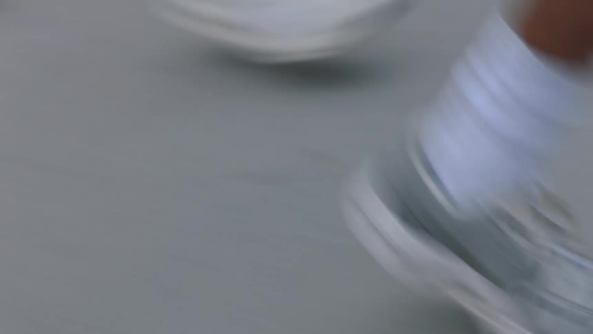 Two people wearing sneakers running side by side on the tarmac on a bright sunny day