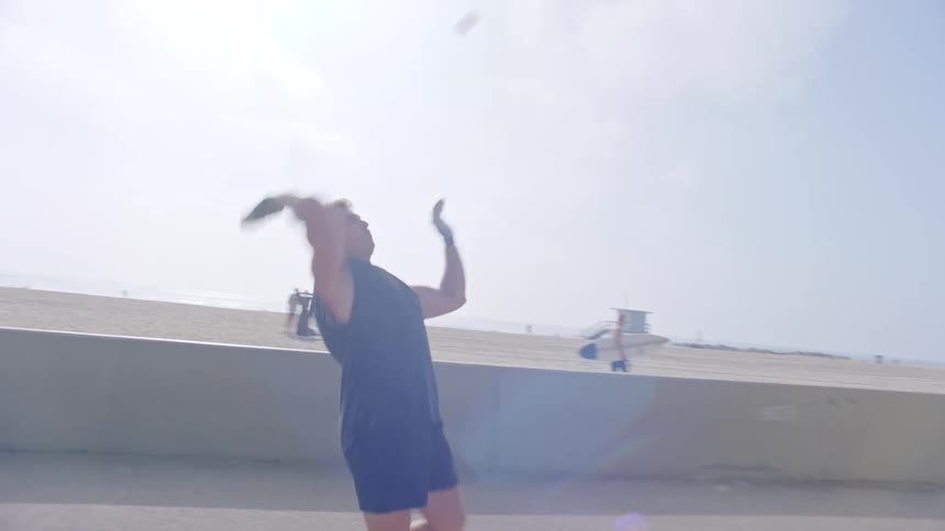 Two men in black shirts are playing a game of hitting a small ball against a wall so it bounces off