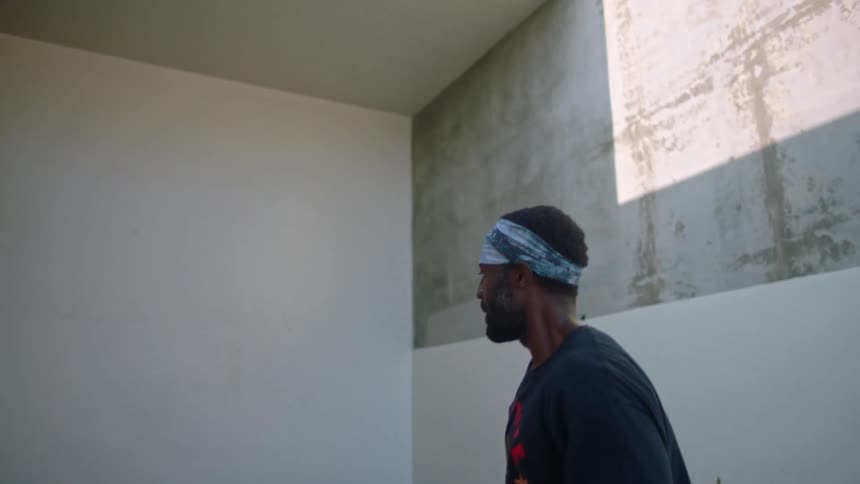 Man wearing gloves is throwing a small ball against the wall