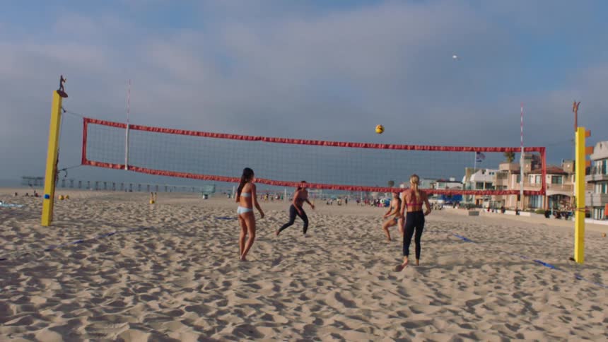 Two pairs of women playing volleyball on the beach
