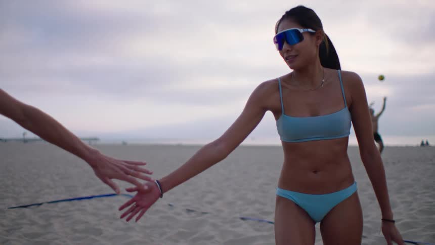 A woman in a blue bikini shaking hands with the person next to her