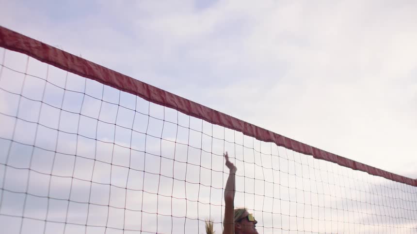 A young woman playing volleyball at an outdoor court during daytime