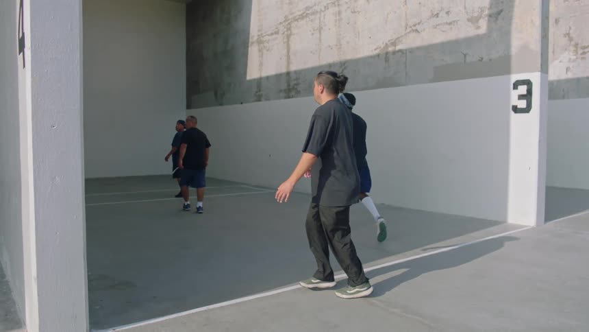 Group of men playing handball on an outdoor handball court at midday