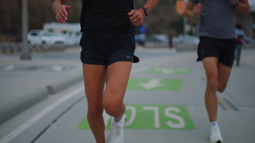 A man and a woman are running on a path with some green stripes drawn on the ground