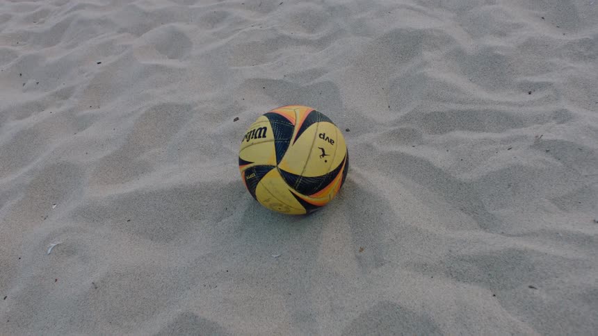 Volleyball lying on the sand at the beach