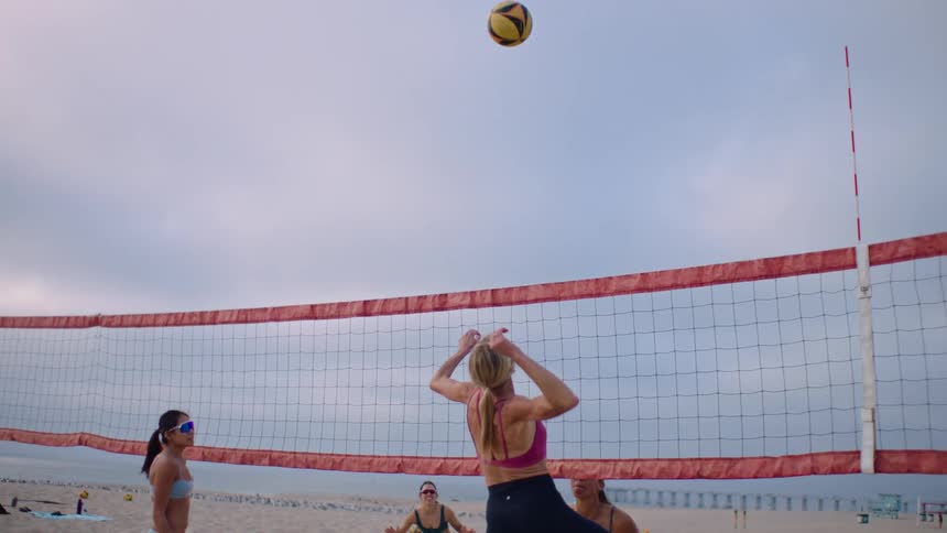 Four women playing beach volleyball on a cloudy day