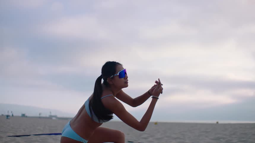Close up of a young asian woman playing volleyball at the beach during daytime