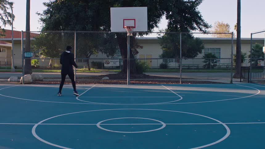 The man playing basketball on a blue court is hitting the shot on the hoop