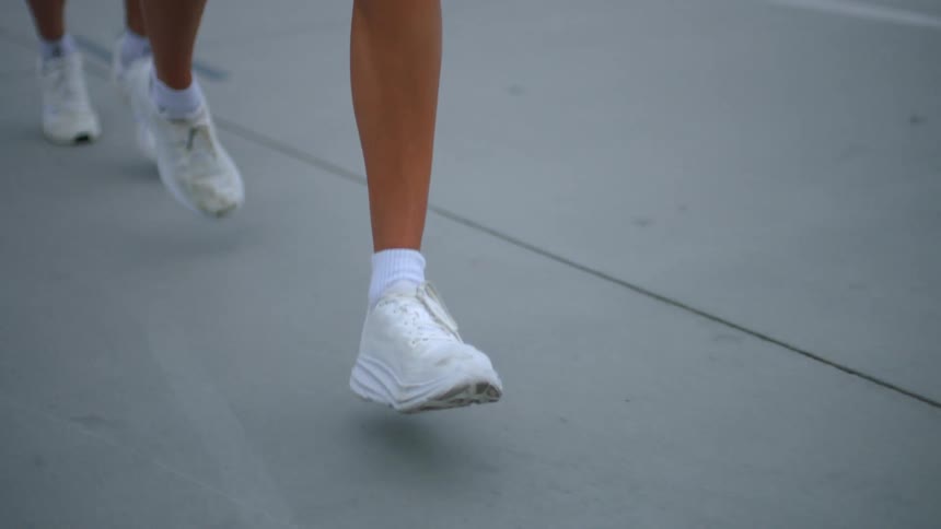 Three people wearing sneakers running outdoors at midday