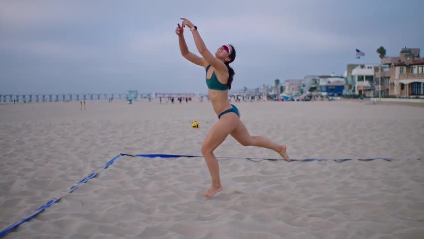 A woman runs after a volleyball