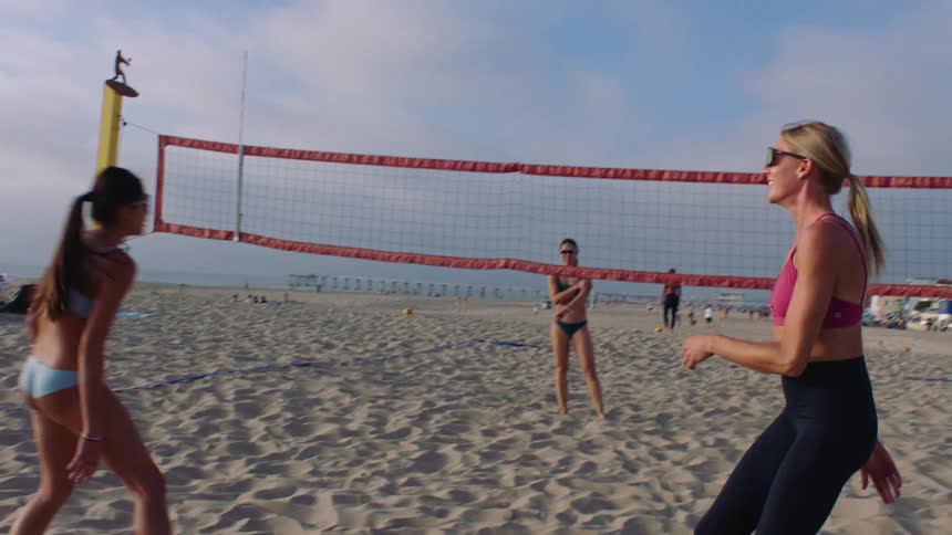 Two volleyball players clapping their hands together during a match on a sand court