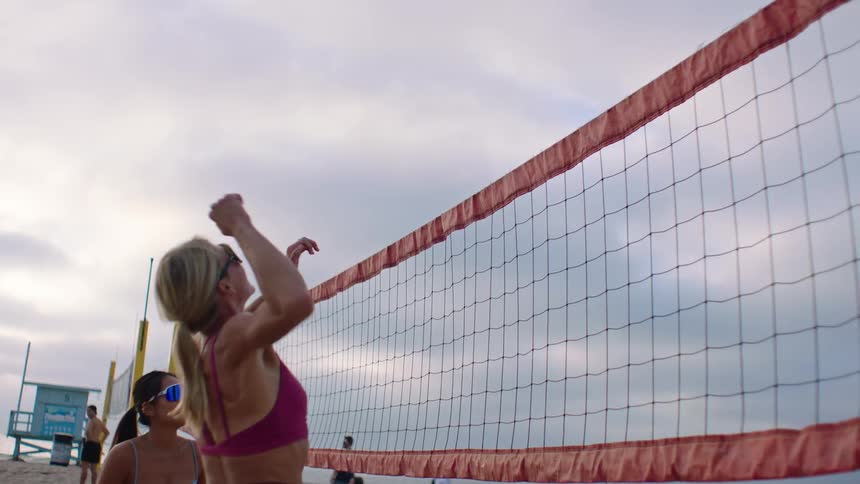 Women play volleyball on the beach on a cloudy summer day
