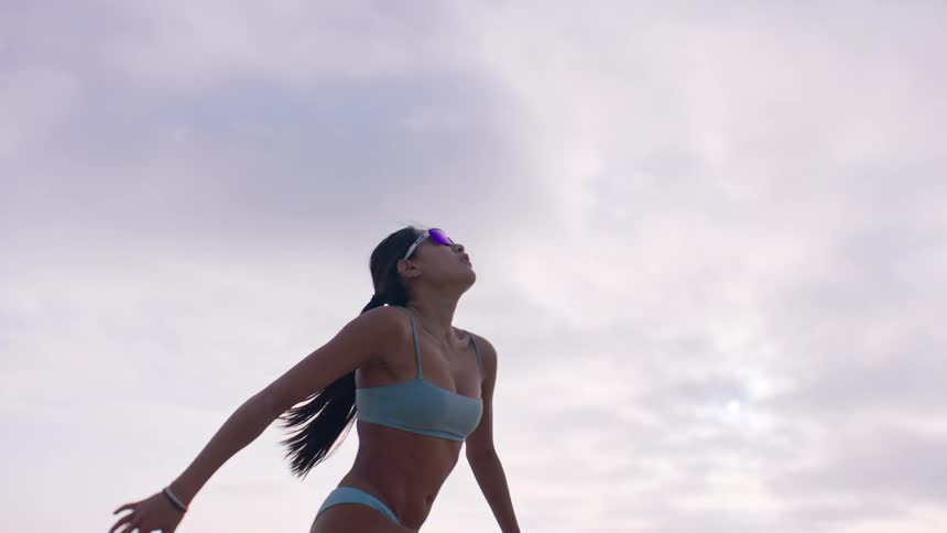 A woman is hitting a yellow ball while playing volleyball