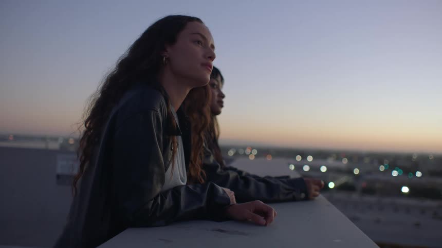 Two women observe the horizon at dusk