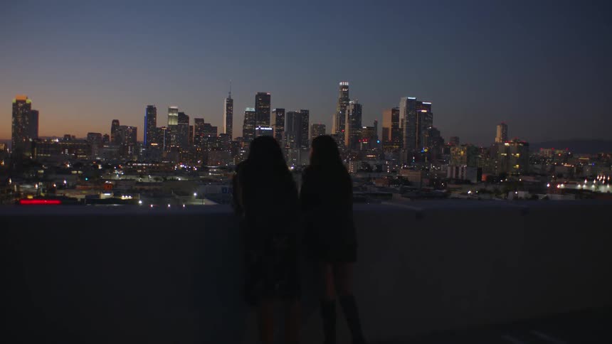 Two women sitting outdoors overlooking a city