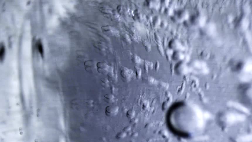 Water with bubbles adhered to a transparent surface seen in closeup