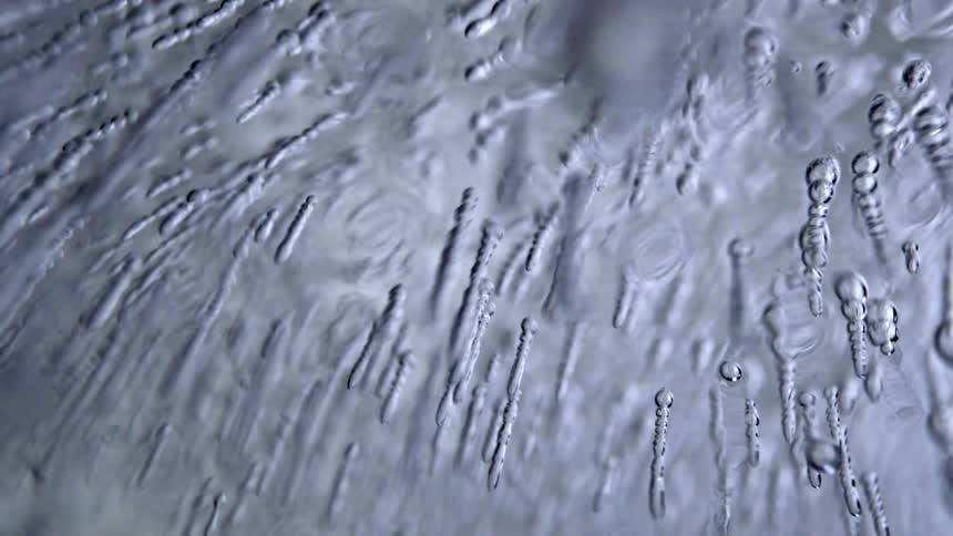 Closeup of abstract rippling liquid forming elongated bubbles and textured patterns