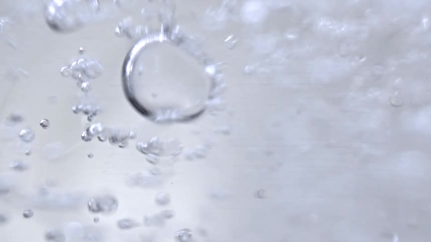 Air bubbles rising in clear liquid seen in closeup