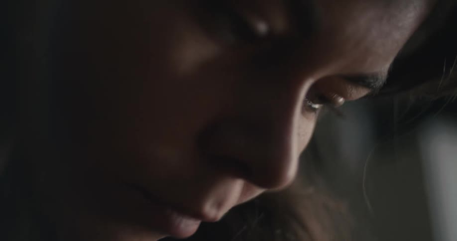 A womans face is looking down and her skin is reflecting natural light