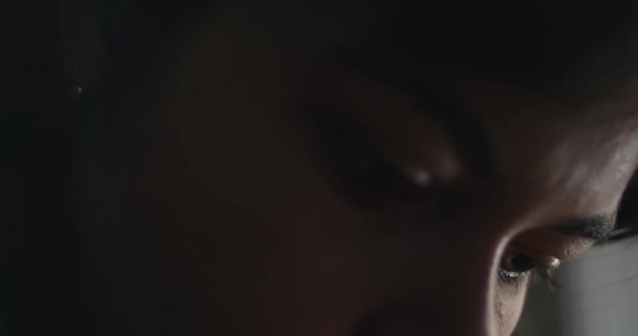 Young woman indoors looking down at the floor with a quiet sad expression