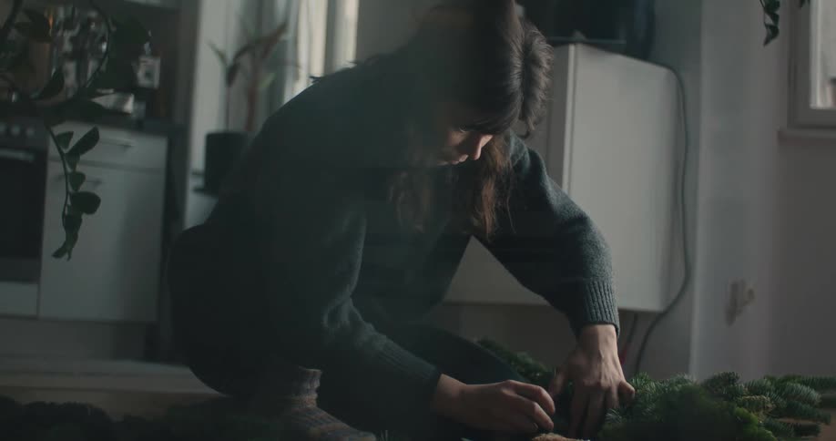 The woman is putting together a wreath at home