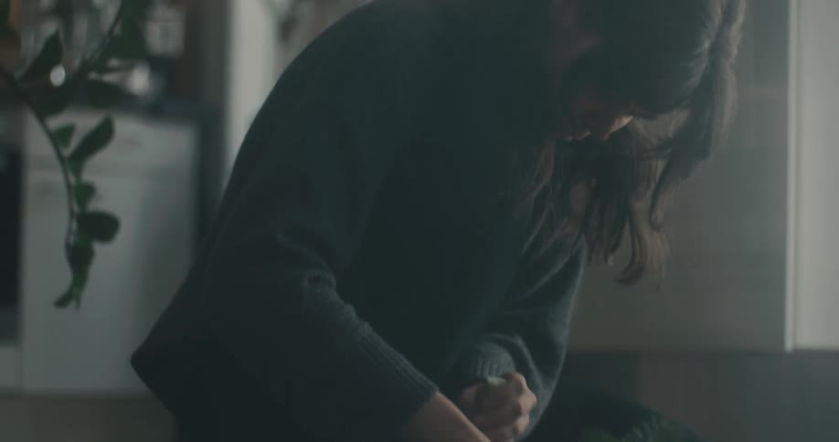 Adult woman squatting on the floor in a room arranging branches from a tree in a decorative manner indoors during day time