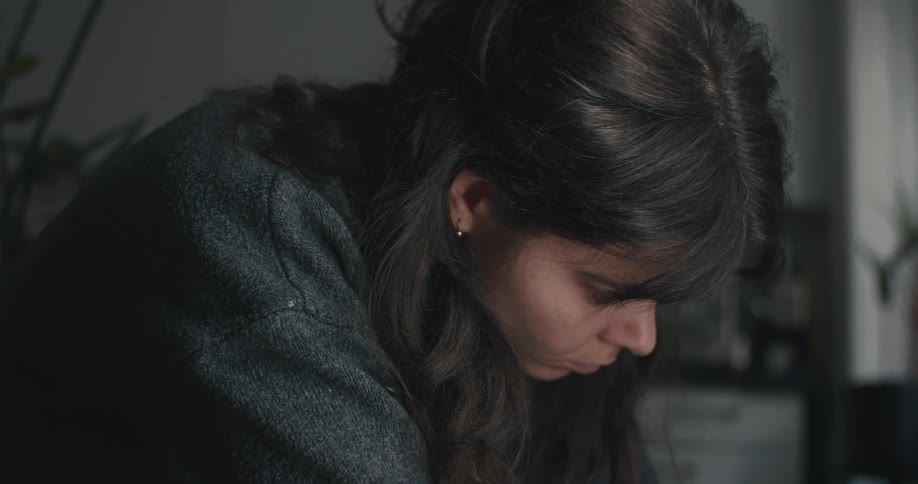Person leaning forward focused on a manual task in an indoor setting