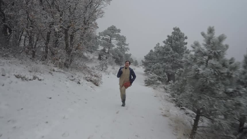 A man joyfully runs along a snow covered trail through a winter forest