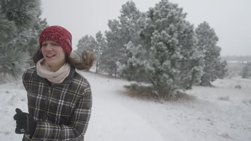 Woman running through the snow with a happy expression