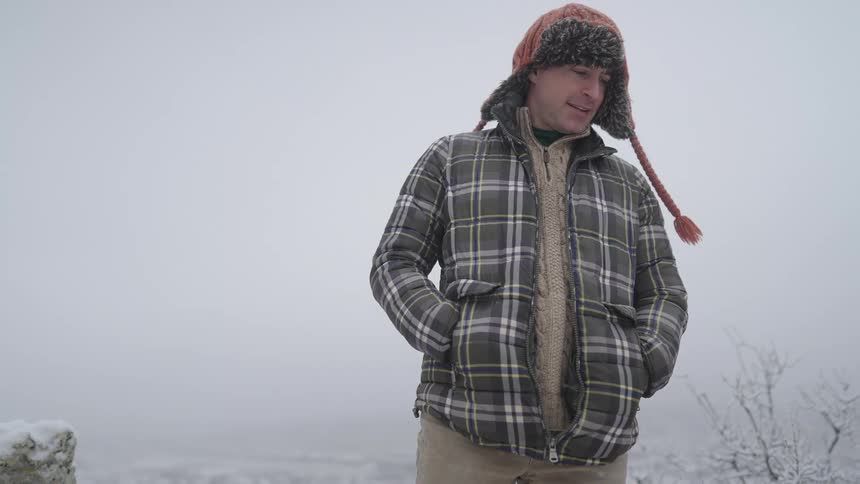 Man outdoors in a snowy environment wearing a padded jacket and winter hat